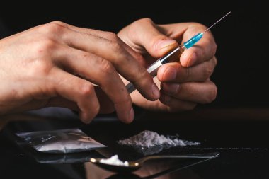 Elinde uyuşturucu şırıngası var. Şırıngada bir doz daha uyuşturucu bulunan bir uyuşturucu bağımlısı. Bağımlı adam, uyuşturucu karşıtı konsept. erkek uyuşturucu bağımlısı.