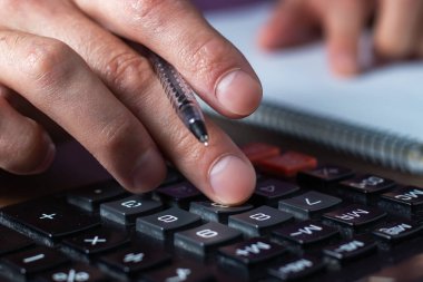 Finansal veri analizi. Ofisteki hesap makinesine güvenen bir iş adamının el yazısının yakın plan fotoğrafı.