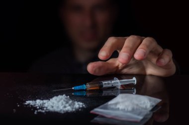 Uyuşturucu karşıtı kavram. Uyuşturucu bağımlısı şırıngadaki ilaçtan bir doz daha alıyor. Adam bağımlı, erkek uyuşturucu bağımlısı, şırınga