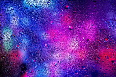 Pencere camındaki yağmur damlaları ve yoğunlaşma neon ışığının arka planına karşı.