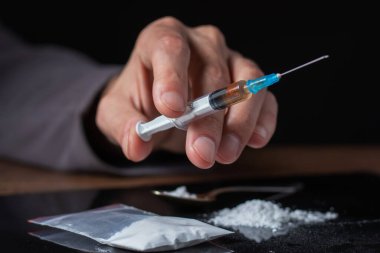 Elinde uyuşturucu şırıngası var. Şırıngada bir doz daha uyuşturucu bulunan bir uyuşturucu bağımlısı. Bağımlı adam, uyuşturucu karşıtı konsept. erkek uyuşturucu bağımlısı.