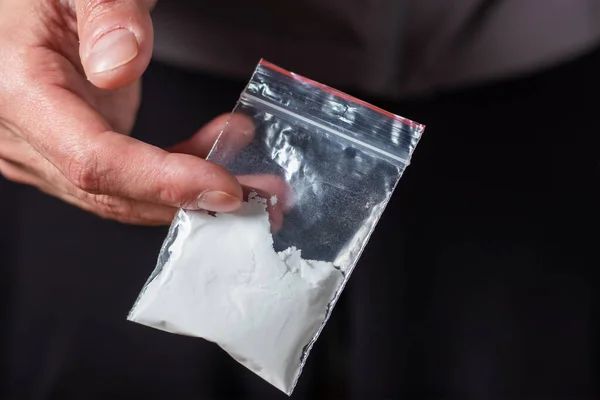 Konsept uyuşturucu bağımlılığı. Bir erkek elinde plastik paket ya da torba kokain ya da başka bir uyuşturucu, uyuşturucu bağımlılığı ve tehlike bağımlılığı kavramı taşır.