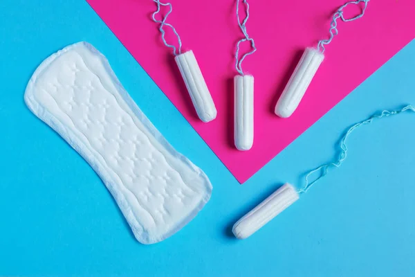 women pads and tampon - sanitary pads lies next to a tampon on an isolated background on a pink and blue background. Women\'s hygiene and menstrual period concept