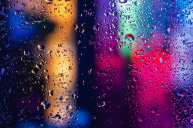 Terli camda bir damla yoğuşma var. Arka planda soğuk sisli cam gece ışıkları.