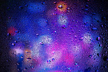 Terli camda bir damla yoğuşma var. Arka planda soğuk sisli cam gece ışıkları.