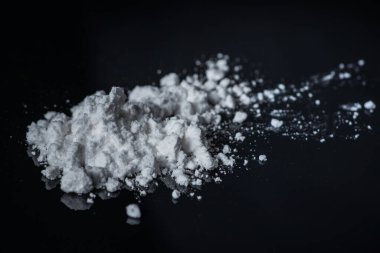 Siyah arka planda kokain tozu yığını.