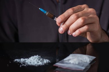 Elinde uyuşturucu şırıngası var. Şırıngada bir doz daha uyuşturucu bulunan bir uyuşturucu bağımlısı. Bağımlı adam, uyuşturucu karşıtı konsept. erkek uyuşturucu bağımlısı.