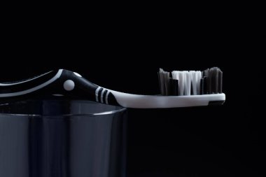 Siyah zemin üzerinde gargara olan siyah ve beyaz bir diş fırçası.