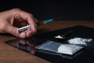 Elinde uyuşturucu şırıngası var. Şırıngada bir doz daha uyuşturucu bulunan bir uyuşturucu bağımlısı. Bağımlı adam, uyuşturucu karşıtı konsept. erkek uyuşturucu bağımlısı.