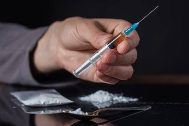 Elinde uyuşturucu şırıngası var. Şırıngada bir doz daha uyuşturucu bulunan bir uyuşturucu bağımlısı. Bağımlı adam, uyuşturucu karşıtı konsept. erkek uyuşturucu bağımlısı.