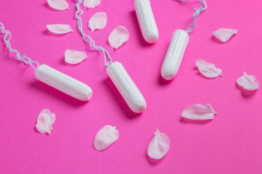 Pembe arka planda kiraz yaprakları olan kadın tamponları. Kadınlar için hijyenik beyaz tampon. Pamuklu çubuk. Regl, pembe arka planda tamponlar..