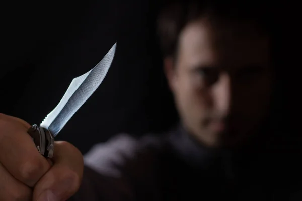 Knife in the hand of a man. Threat with knife. Man attack with knife. Crime, violence. Selective focus. Blurred face