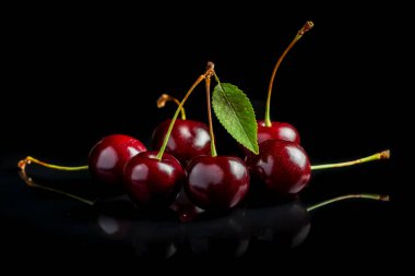 Sweet cherries with cherry leaf on a black background