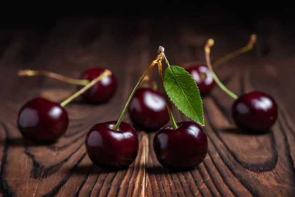 Sweet cherries with cherry leaf on a wooden background