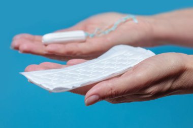 Woman holding a menstruation cotton tampon and gasket in her hand. Hygiene and protection.