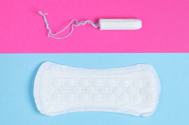 Kadın pedleri ve tamponları - hijyenik pedlerin yanında pembe ve mavi arka planda izole edilmiş bir tampon bulunur. Kadın hijyeni ve adet dönemi konsepti