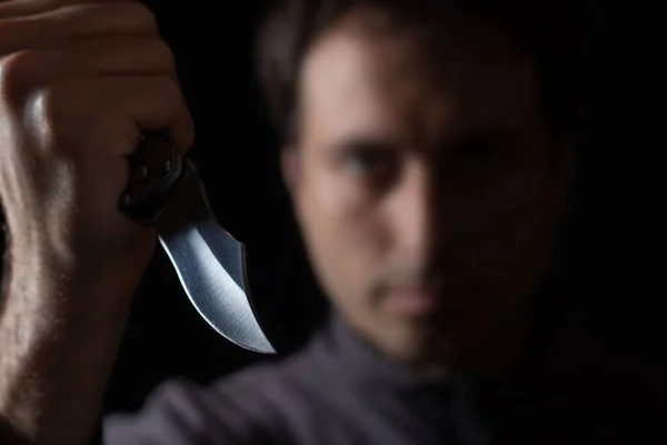 Knife in the hand of a man. Threat with knife. Man attack with knife. Crime, violence. Selective focus. Blurred face