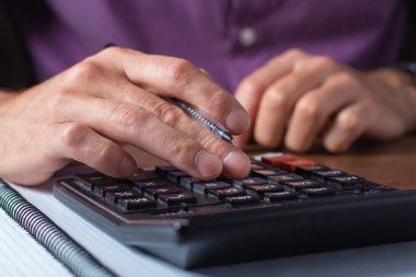 Finansal veri analizi. Ofisteki hesap makinesine güvenen bir iş adamının el yazısının yakın plan fotoğrafı.