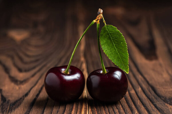 Sweet cherries with cherry leaf on a wooden background
