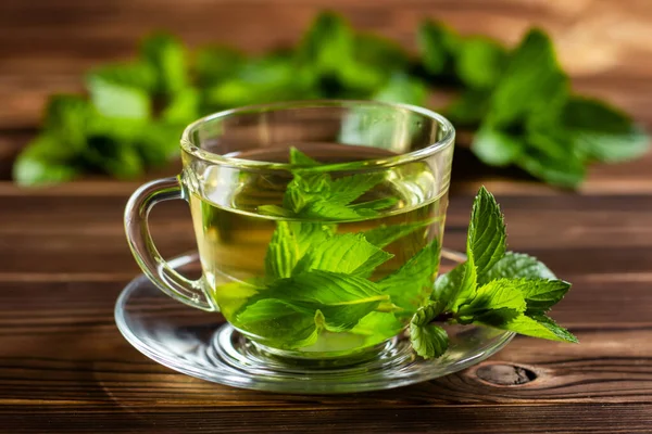 Cup of mint tea and a bunch of mint on the table.