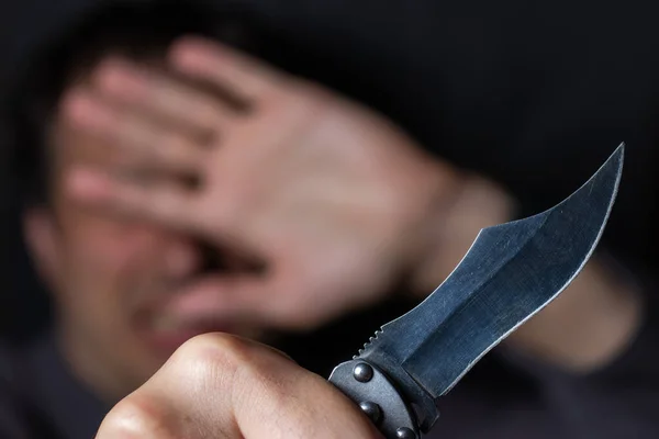 Knife in the hand of a man. Threat with knife. Man attack with knife. Crime, violence. Selective focus. Blurred face