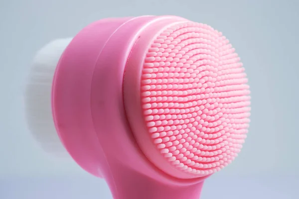 Pink face cleansing brush, closeup. Cosmetic accessory.