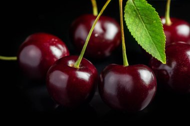 Sweet cherries with cherry leaf on a black background
