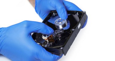 Hard diski tamir et. Eldiven ustasının elleri bilgisayarın sabit diskini tamir ediyor. Veri temizleme, HDD kurtarma