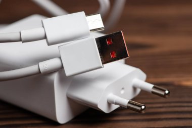 Tahta arka planda USB kablosu olan beyaz şarj aleti.