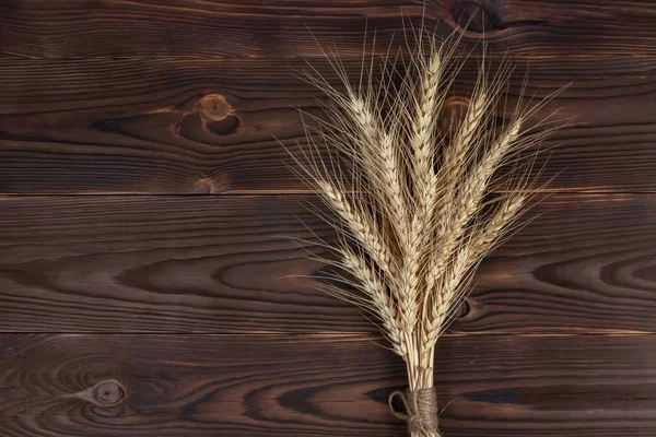 Wheat Ears on the Wooden Table. Sheaf of Wheat over Wood Background. Harvest concept.