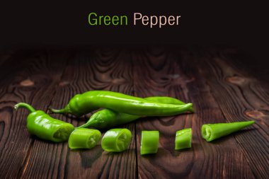 Ahşap arka planda dilimleri olan yeşil kırmızı biber..