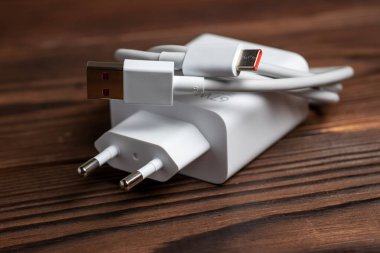 Tahta arka planda USB kablosu olan beyaz şarj aleti.