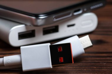 Mobil cihazları şarj etmek için USB kablosu ve akıllı telefonu olan taşınabilir güç bankası.
