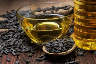 Cam kasede ayçiçeği yağı ve tahta arka planda tahta kaşıkta tohum..