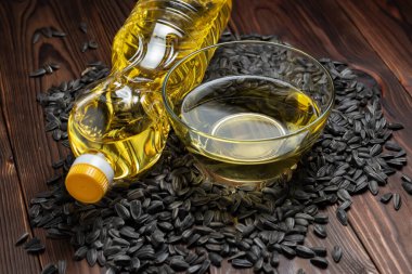 Cam kasede organik ayçiçeği yağı ve ayçiçeği tohumlarıyla dolu bir şişe.