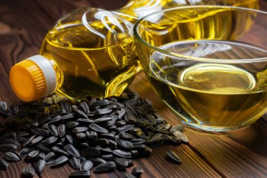 Cam kasede organik ayçiçeği yağı ve ayçiçeği tohumlarıyla dolu bir şişe.