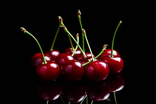 Red cherry berries on a black background with mirror. Three cherries.