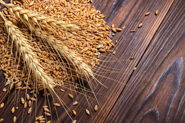 Ripe ears of cereals and grains. Wheat ears, rye, barley and oats on wooden background, top view.