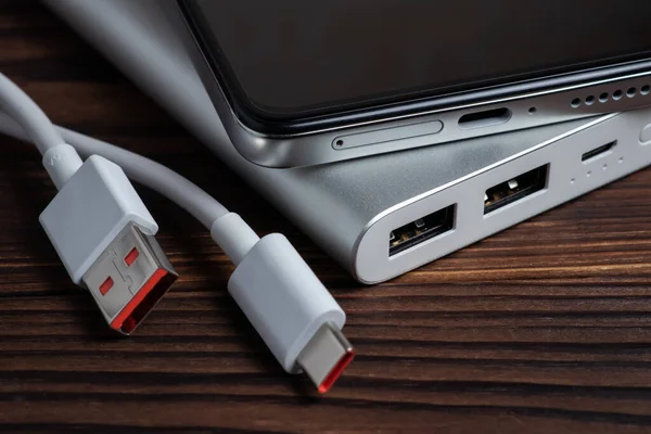 Mobil cihazları şarj etmek için USB kablosu ve akıllı telefonu olan taşınabilir güç bankası.