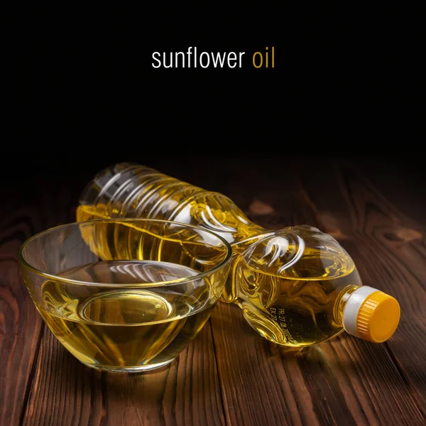 Sunflower oil in bottles with glass bowl on wooden background.