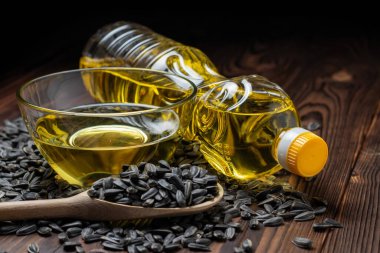 Cam kasede ayçiçeği yağı ve tahta arka planda tahta kaşıkta tohum..