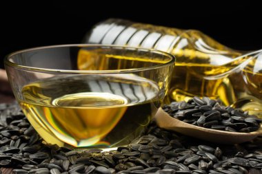 Cam kasede ayçiçeği yağı ve tahta arka planda tahta kaşıkta tohum..