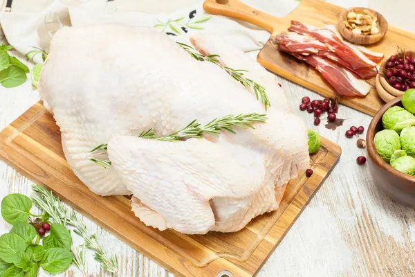 Pavo crudo entero en tabla de cortar de madera —  Fotos de Stock