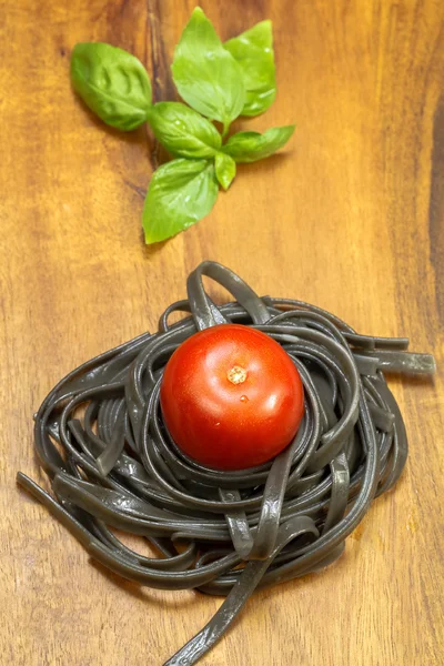 Zwarte spaghetti nest met tomaat — Stockfoto