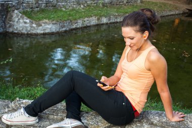 Park earphones ile Smartphone kullanan genç kadın