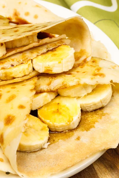 Pancakes or crepes with banana, maple syrup and sugar powder — Stock Photo, Image