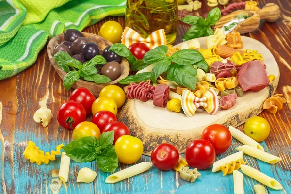 Итальянская паста с помидорами, оливковым маслом и оливками на деревенской деревянной доске — стоковое фото