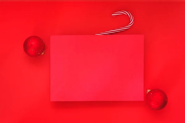 Empty red background and blank Christmas paper sheet with red baubles on red background. Minimal concept. Advertising template. Top view, place for text