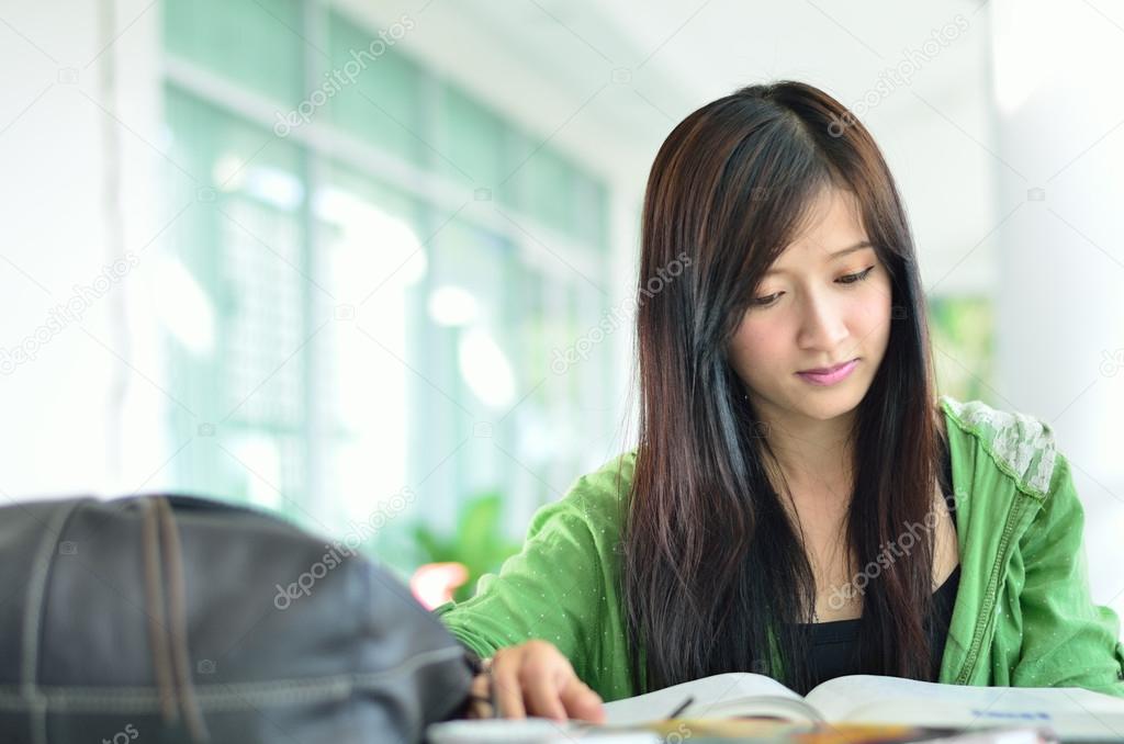 Beautiful asian girl is reading and smile