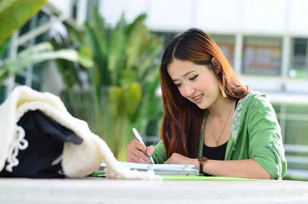 Bella giovane studente asiatico sta leggendo e scrivendo — Foto Stock